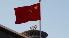 Čínská vlajka před Olympijskou věží se symbolem pěti kruhů v Pekingu