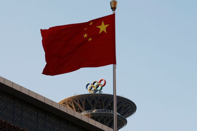 Čínská vlajka před Olympijskou věží se symbolem pěti kruhů v Pekingu