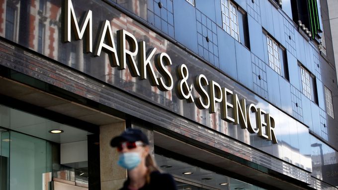 Žena v roušce míjí obchod britské značky Marks & Spencer v Londýně.