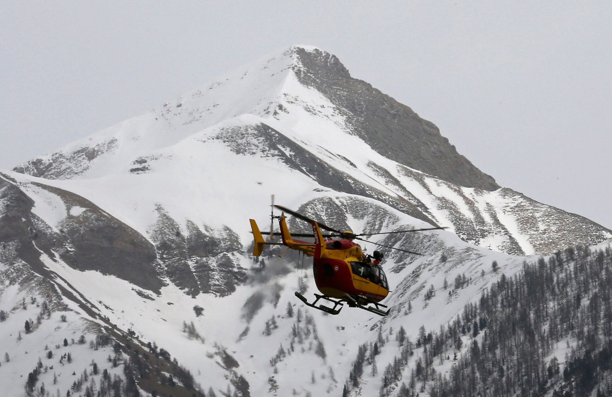 A rescue helicopter from the French Securite Civile flies over the French Alps during a rescue operation next to the crash site of an Airbus A320
