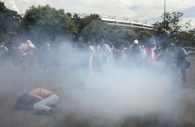 Members of the media film a supporter of a native Indian community living at the Brazilian Indian Museum as she lies amid tear gas during clashes with military police officers as they protest against the community's eviction in Rio de Janeiro March 22, 2013. Brazilian military police took position early morning outside the abandoned museum, where the community of around 30 native Indians have been living in since 2006. The community was ordered to leave the museum in 72 hours by court officials since last week, local media reported. Most of the Indians later left the museum after making a deal with the authorities. REUTERS/Ricardo Moraes (BRAZIL - Tags: MEDIA CIVIL UNREST POLITICS SOCIETY REAL ESTATE BUSINESS) Published: Bře. 22, 2013, 5:04 odp.