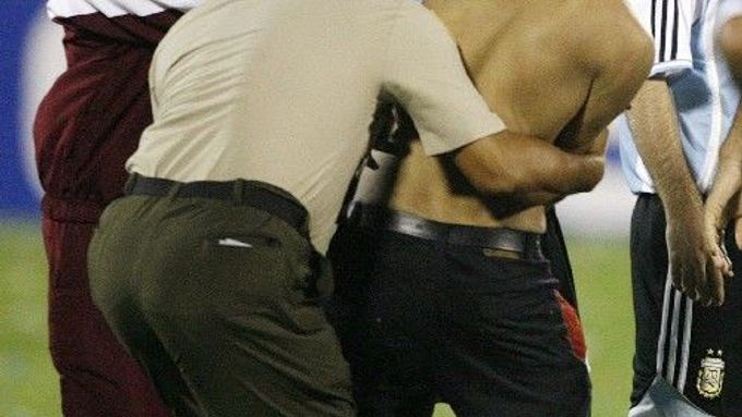 Fanoušek, který vtrhl na hřiště při zápase Argentina USA, se snaží obejmout Roberta Ayalu.