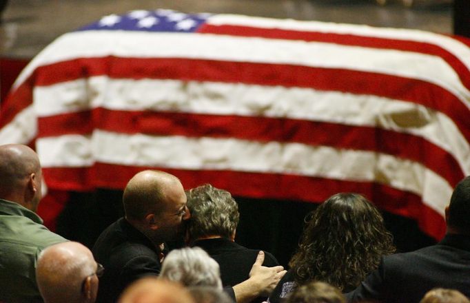 Aaron Poland, son of murdered bus driver Charles Albert Poland Jr., hugs and kisses his mom Mary Janice Poland moments after the casket containing Poland Jr.'s body is presented at Ozark Civic Center, near Midland City, Alabama, February 3, 2013. Mourners in the small town of Midland City, Alabama, gathered on Sunday to bury a school bus driver slain during the abduction of a child taken captive and held for a sixth day by a gunman in an underground bunker. REUTERS/Phil Sears (UNITED STATES - Tags: CRIME OBITUARY) Published: Úno. 4, 2013, 12:37 dop.