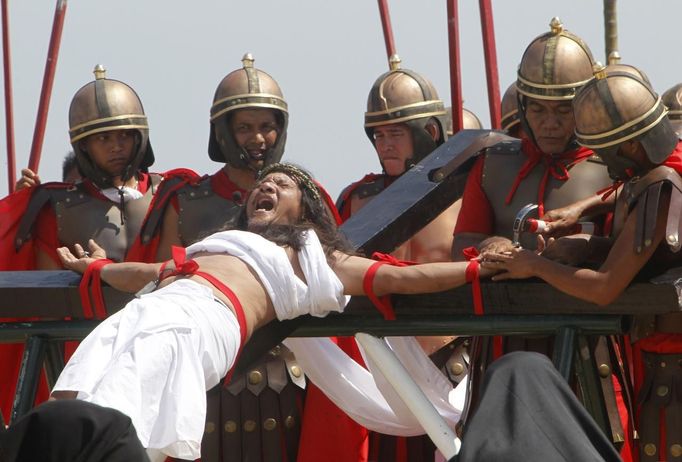 Ruben Enaje, 52, who is portraying Jesus Christ for the 27th time, screams while a man who plays a Roman soldier hammers a nail into his palm during a Good Friday crucifixion re-enactment in San Pedro Cutud town, Pampanga province, north of Manila March 29, 2013. The Roman Catholic church frowns upon the gory spectacle held in the Philippine village of Cutud every Good Friday but does nothing to deter the faithful from emulating the suffering of Christ and taking a painful route to penitence. Holy Week is celebrated in many Christian traditions during the week before Easter. REUTERS/Romeo Ranoco (PHILIPPINES - Tags: RELIGION SOCIETY TPX IMAGES OF THE DAY) Published: Bře. 29, 2013, 7:24 dop.