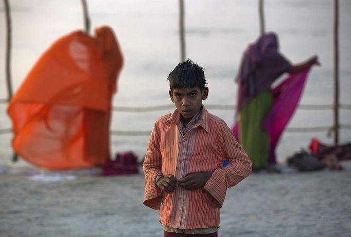 A boy unbuttons his shirt to take a holy dip in the waters of the Ganges river ahead of the "Kumbh Mela", or Pitcher Festival, in the northern Indian city of Allahabad January 10, 2013. During the festival, hundreds of thousands of Hindus take part in a religious gathering at the banks of the river Ganges. The festival is held every 12 years in different Indian cities. REUTERS/Ahmad Masood (INDIA - Tags: RELIGION SOCIETY) Published: Led. 10, 2013, 8:32 dop.