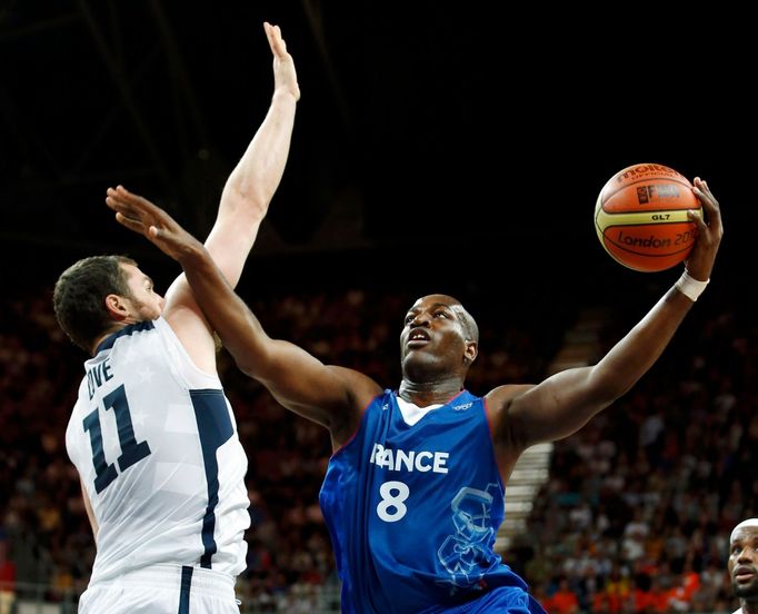 Francouzský basketbalista Ali Traore se snaží smečovat přes Američana Kevina Loveho v utkání základní skupiny A mezi USA a Francií na OH 2012 v Londýně.