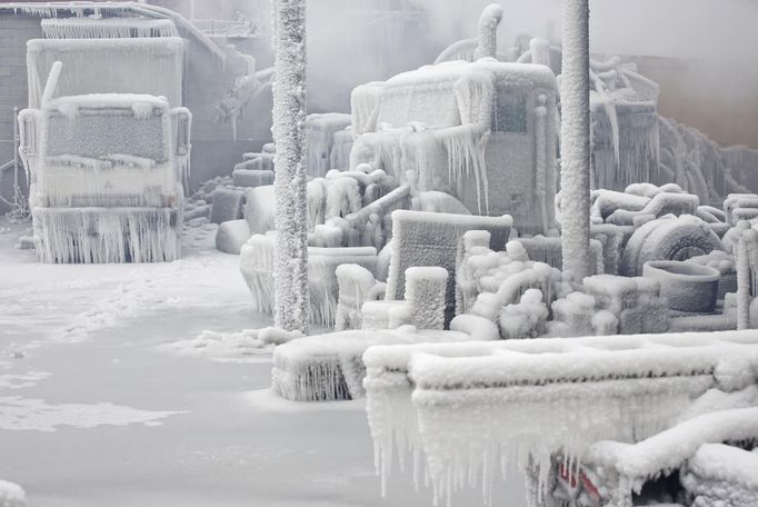 Ice-covered trucks are blanketed in smoke after a warehouse fire in Chicago January 23, 2013. Fire department officials said it is the biggest fire the department has had to battle in years and one-third of all Chicago firefighters were on the scene at one point or another trying to put out the flames. An Arctic blast continues to grip the U.S. Midwest and Northeast Wednesday, with at least three deaths linked to the frigid weather, and fierce winds made some locations feel as cold as 50 degrees below zero Fahrenheit. (minus 46 degrees Celsius). REUTERS/John Gress (UNITED STATES - Tags: DISASTER ENVIRONMENT) Published: Led. 23, 2013, 6:02 odp.