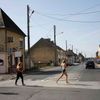 Girls run across the street at the junction of Rue Holgate and RN13 in the Normandy town of Carentan