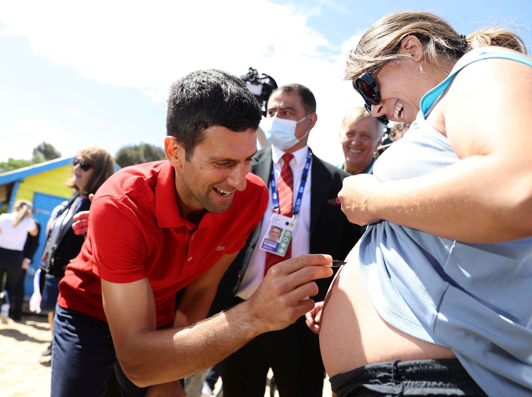 Novak Djokovič se podepisuje na bříško těhotné fanynky při akci na Brighton Beach v Melbourne po vítězství na Australian Open
