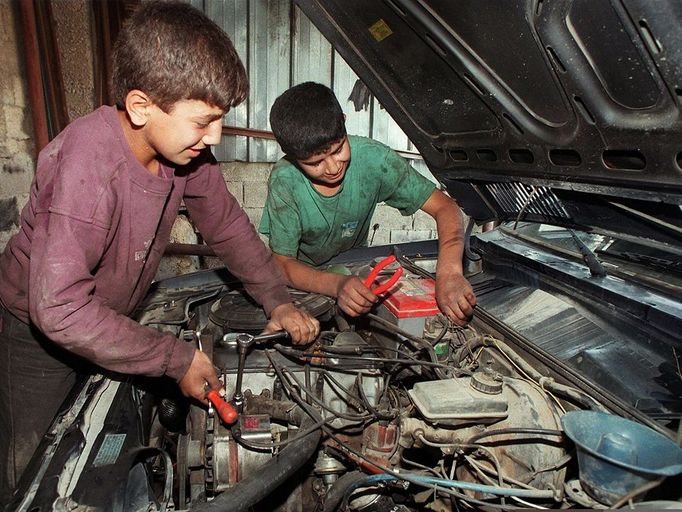 deux jeunes enfants palestiniens travaillent dans un garage de Jerusalem est le 30 octobre 1997. Two Palestinian children repair a car engine in a garage in East Jerusalem, 30 October. The International Labour Organisation has warned of increasing child labour in the West Bank and Gaza, saying some seven percent of Palestinian children work, often long hours in dangerous conditions.