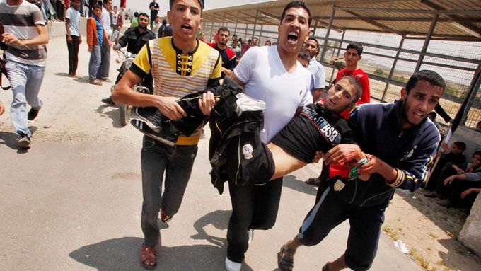 Muži odnášejí Palestince, který byl postřelen při střetu demonstrantů a izraelských ozbrojených sil u hraničního přechodu Eréz na severu pásmu Gazy.