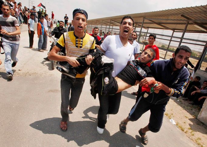 Muži odnášejí Palestince, který byl postřelen při střetu demonstrantů a izraelských ozbrojených sil u hraničního přechodu Eréz na severu pásmu Gazy.