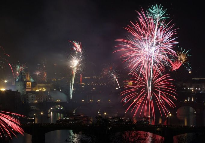 Půlnoční ohňostroj nad pražskými mosty přes Vltavu. Petardy odpalovali všichni - turisté i obyvatelé, ze souše, z mostů i z lodí na řece.