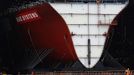 Workers watch as the forward section of the aircraft carrier HMS Queen Elizabeth is moved onto a barge at HM Naval Base in Portsmouth, southern England May 14, 2012. The hull will be transported by a sea going barge to Rosyth in Scotland where the ship will be assembled in dry dock. REUTERS/Luke MacGregor (BRITAIN - Tags: BUSINESS EMPLOYMENT MILITARY) Published: Kvě. 14, 2012, 2:27 odp.