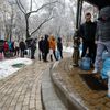 Lidé v Kyjevě čekají ve frontě, aby si naplnili plastové láhve vodou.