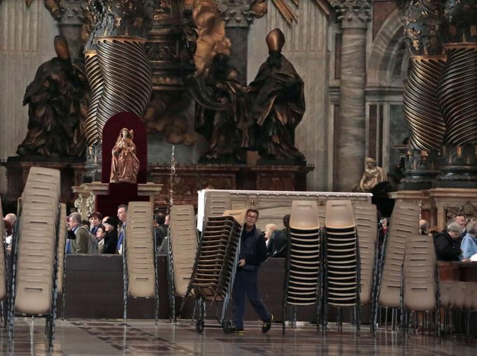 A worker carries chairs inside Saint Peter's Basilica during the preparations for the election of the new Pope at the Vatican March 11, 2013. Roman Catholic Cardinals will begin their conclave inside the Sistine Chapel on Tuesday to elect a new pope. REUTERS/Eric Gaillard (VATICAN - Tags: RELIGION) Published: Bře. 11, 2013, 1:05 odp.