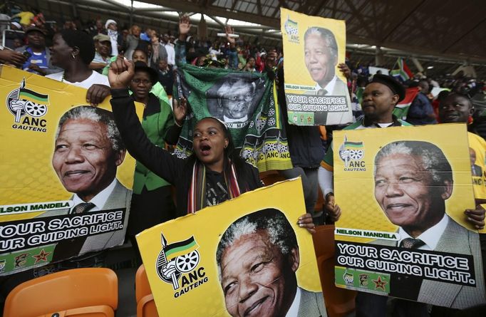 People hold placards of former South African President Nelson Mandela at the First National Bank (FNB) Stadium, also known as Soccer City, during the national memorial service for Mandela in Johannesburg December 10, 2013.