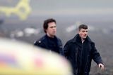 Policista doprovází jednoho ze zraněných pasažérů Turkish Airlines z pole, kam se letoun zřítil.
