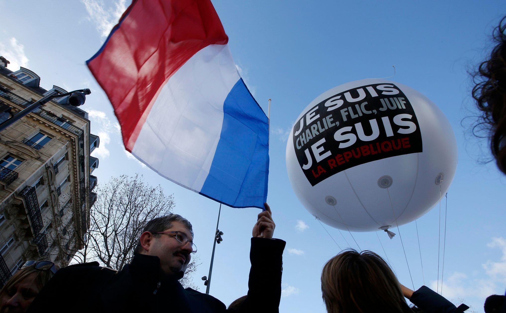 People hold a balloon and a French flag as they attend the solidarity march in the streets of Paris