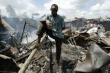 Muž stojí uprostřed rumiště poté, co se částí nairobského slumu Mathare prohnal požár.