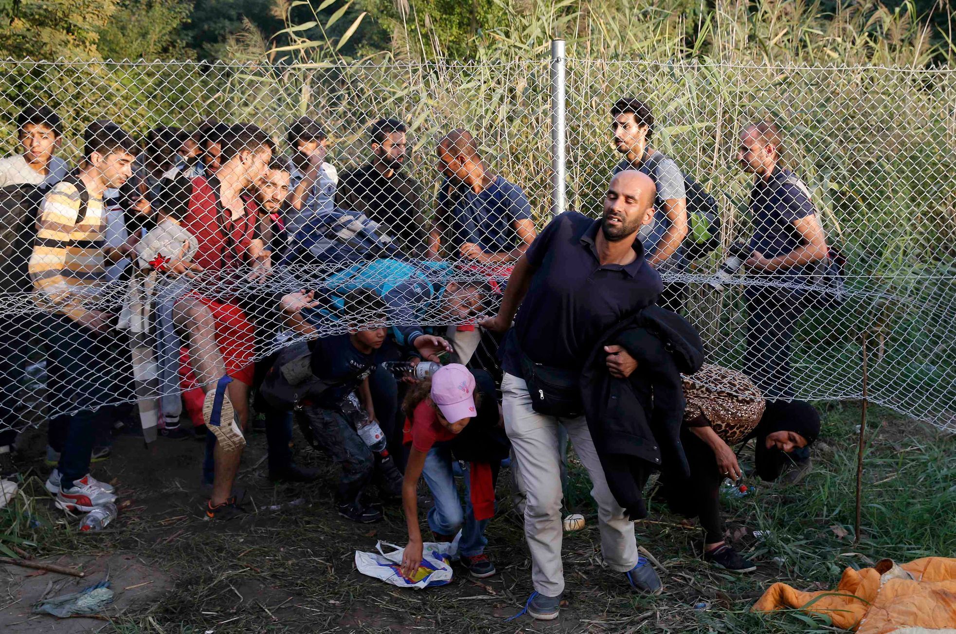 Běženci prolézají pod plotem ze Srbska do Maďarska