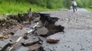 A woman stands in a sunken street after flooding in Duluth, Minnesota, June 20, 2012. Heavy rains pounded northern Minnesota on Wednesday, forcing the evacuation of dozens of homes, causing mudslides and sinkholes, and swamping a zoo where several animals died, officials said. Picture taken June 20, 2012. REUTERS/Joe Cadotte (UNITED STATES - Tags: DISASTER SOCIETY ENVIRONMENT) Published: Čer. 21, 2012, 10:48 odp.