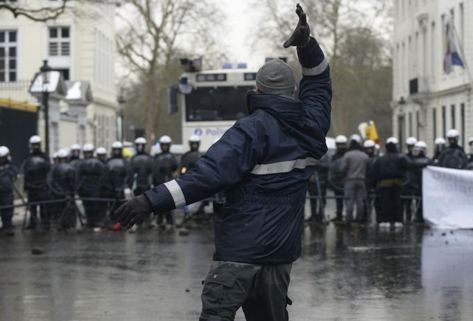 An Arcelor Mittal worker from Liege gestures in front of riot police during a demonstration outside Prime Minister Elio Di Rupo's office in Brussels January 25, 2013. ArcelorMittal, the world's largest steel producer, plans to shut a coke plant and six finishing lines at its site in Liege, affecting 1,300 employees, the group said on Thursday. REUTERS/Eric Vidal (BELGIUM - Tags: BUSINESS CIVIL UNREST EMPLOYMENT) Published: Led. 25, 2013, 2:37 odp.