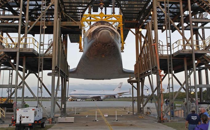 Space center workers watch as the space shuttle Discovery is elevated in the Mate Demate facility at Kennedy Space Center in Cape Canaveral