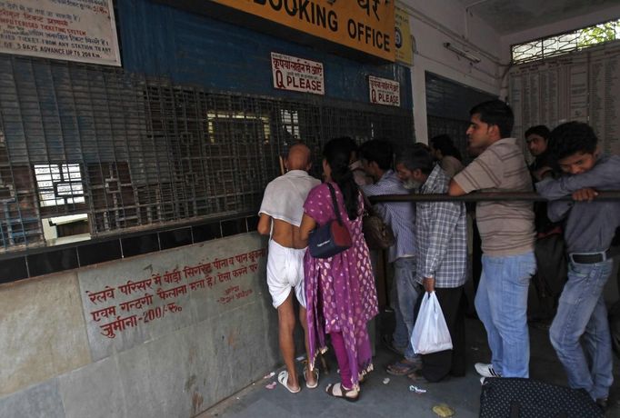 Mahesh Chaturvedi (L), 63, who dresses up like Mahatma Gandhi, stands in a queue at the railway station in New Delhi September 28, 2012. Chaturvedi says that the soul of Gandhi resides in him and he has been sent to continue the work of Father of the Nation. After his self proclaimed transformation in 2002 as Gandhi, Chaturvedi has been travelling extensively and plays up to his startling resemblance to Gandhi at protests and demonstrations. Picture taken September 28, 2012. REUTERS/Mansi Thapliyal (INDIA - Tags: SOCIETY) Published: Lis. 26, 2012, 3:55 dop.