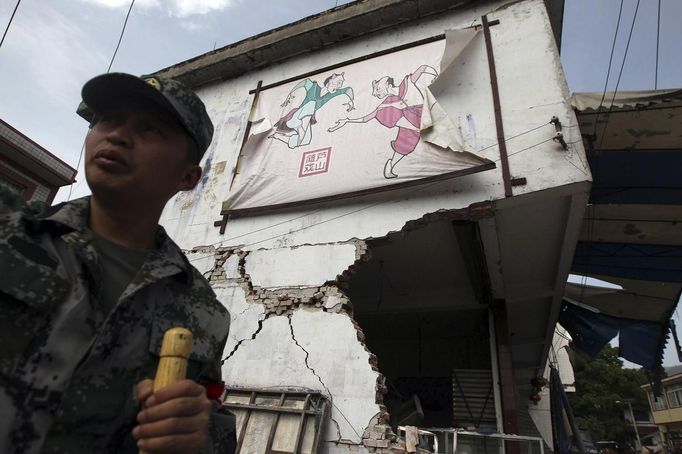 A rescue worker stands in front of damaged houses after a strong 6.6 magnitude earthquake, at Longmen village, Lushan county, Ya'an, Sichuan province April 20, 2013. The earthquake hit a remote, mostly rural and mountainous area of southwestern China's Sichuan province on Saturday, killing at least 102 people and injuring about 2,200 close to where a big quake killed almost 70,000 people in 2008. REUTERS/Stringer (CHINA - Tags: DISASTER) CHINA OUT. NO COMMERCIAL OR EDITORIAL SALES IN CHINA Published: Dub. 20, 2013, 9:18 dop.