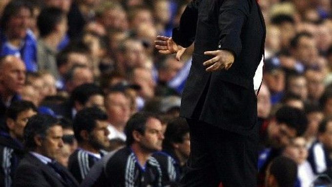 Kouč Chelsea José Mourinho (vlevo) sedí na lavičce, zatímci jeho liverpoolský protějšek Rafael Benitez živě reaguje na dění na hřišti.