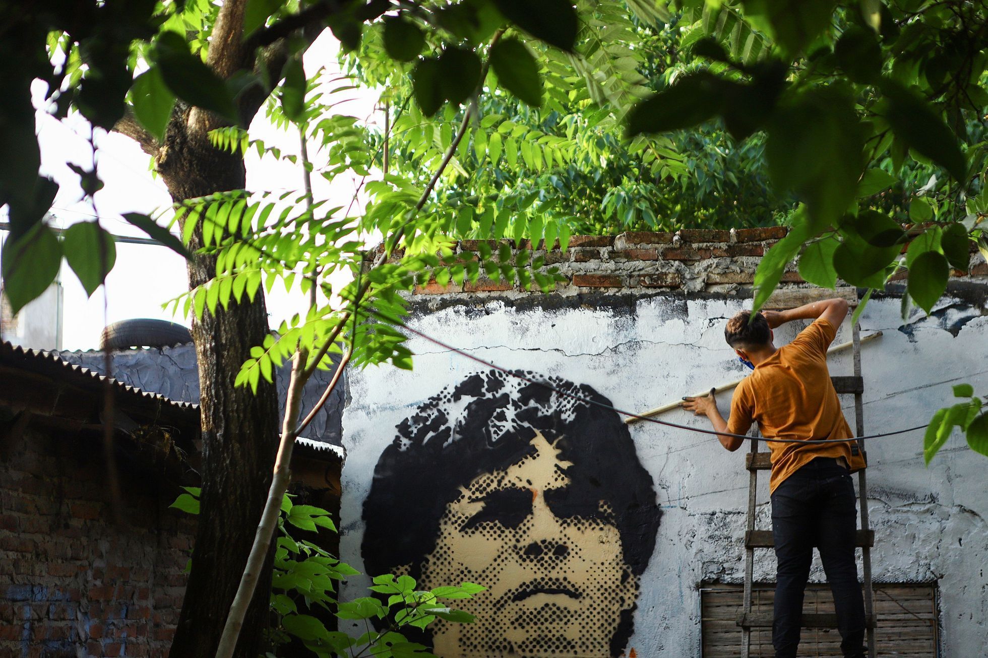 An artist paints a mural of soccer legend Diego Maradona on a wall of the house where Maradona spent his childhood on the outskirts of  Buenos Aires