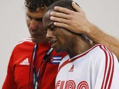 Plačícího kubánského fotbalistu Livana Vasconcelose uklidňuje kouč po porážce od Hondurasu.