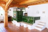 V přízemí je velká společenská místnost s kuchyní a pecí s tmavě zelenými, keramickými obklady.
