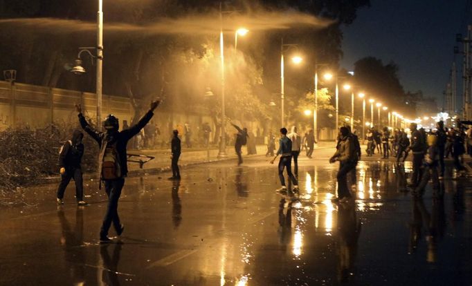 Protesters opposing Egyptian President Mohamed Mursi and the Muslim Brotherhood chant anti-government slogans while police spray water on them from inside the Presidential Palace, as some of the protesters try to break through one of the gates of the palace, in Cairo February 11, 2013. Protesters demanding the departure of Mursi clashed with police outside his palace on Monday on the second anniversary of the overthrow of veteran autocrat Hosni Mubarak. Dozens of youths threw rocks at the Ettihadiya palace after a peaceful march by thousands of demonstrators who accused Mursi's conservative Muslim Brotherhood of hijacking Egypt's democratic revolution and seeking to monopolise power. REUTERS/Asmaa Waguih (EGYPT - Tags: POLITICS CIVIL UNREST) Published: Úno. 11, 2013, 8:55 odp.