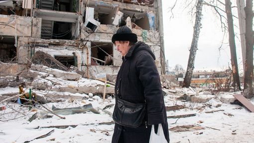 Pohled na kráčející ženu nedaleko vybombardovaného obytného domu v Charkově na Ukrajině. 13. 3. 2022
