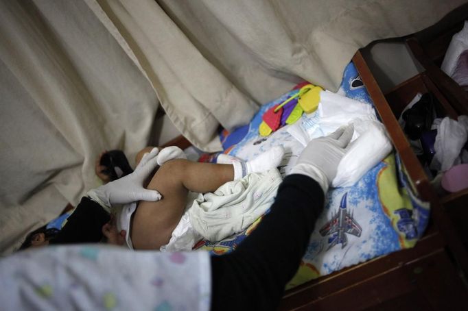 A nurse changes a child's diaper at the San Jose Hospice, in Sacatepequez, 45 km (28 miles) of Guatemala City, November 30, 2012. About 68 HIV-infected children receive free medical care at the hospice, many of them were found abandoned in markets, churches, fire stations, left neglected in hospitals or in some instances, brought in by their families who cannot afford to pay for their medical treatment. World AIDS day which falls on December 1 is commemorated across the world to raise awareness of the pandemic. REUTERS/Jorge Dan Lopez (GUATEMALA - Tags: ANNIVERSARY HEALTH) Published: Pro. 1, 2012, 1:40 dop.