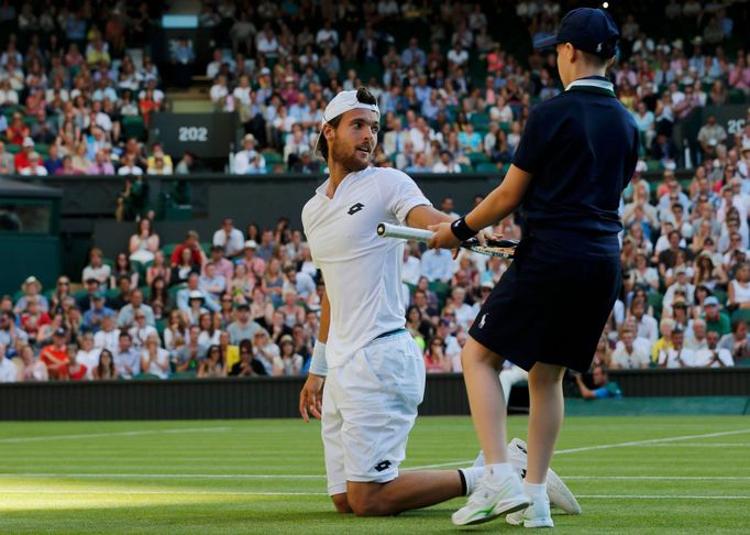 Podavač míčků na Wimbledonu pomáhá Joau Sousovi.