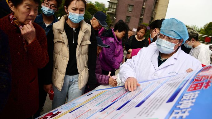 Zdravotník vysvětluje obyvatelům čínského města více informací o vakcíně proti koronaviru.