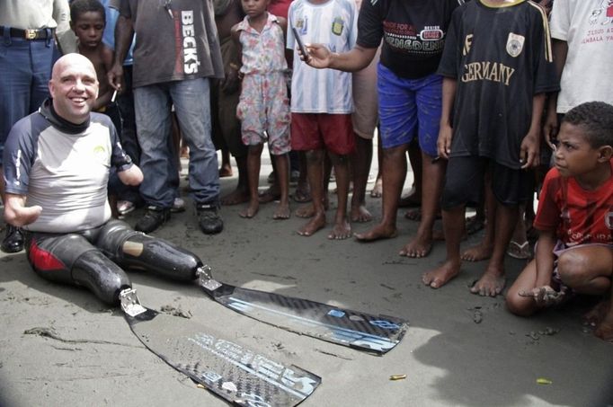 French swimmer Philippe Croizon rests while Papuan residents looks on after his arrival at the coastal village of Pasar Skow located in Indonesia's eastern province of Papua on May 17, 2012. Croizon, 43, who lost his limbs in an accident braved strong winds and currents to swim from Papua New Guinea to Indonesia on May 17, in the first stretch of a mission to swim between five continents. Croizon, who uses prosthetic limbs with flippers attached took seven and a half hours for the 20 kilometre (12-mile) journey.