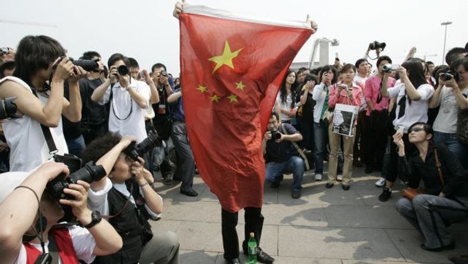 Čína dnes uctila památku obětí zemětřesení třemi miutami ticha. Na snímku drží muž čínskou vlajku na náměstí Tchien an-men v Pekingu.