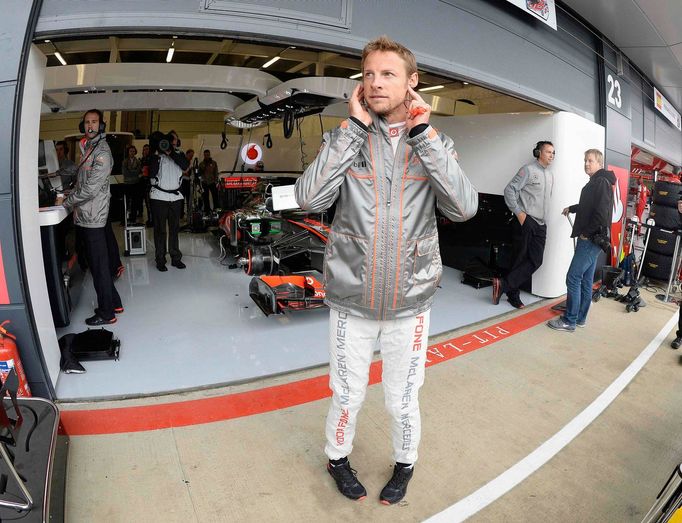 McLaren Formula One driver Jenson Button of Britain watches from the pit lane during first practice ahead of the British Grand Prix at the Silverstone Race circuit, centr