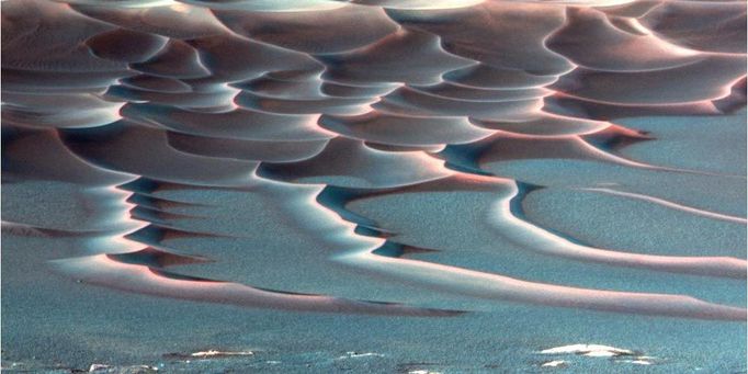 'Endurance Crater's' Dazzling Dunes (false-color) 8/6/04 As NASA's Mars Exploration Rover Opportunity creeps farther into "Endurance Crater," the dune field on the crater floor appears even more dramatic. This false-color image taken by the rover's panoramic camera shows that the dune crests have accumulated more dust than the flanks of the dunes and the flat surfaces between them. Also evident is a "blue" tint on the flat surfaces as compared to the dune flanks. This results from the presence of the hematite-containing spherules ("blueberries") that accumulate on the flat surfaces. Sinuous tendrils of sand less than 1 meter (3.3 feet) high extend from the main dune field toward the rover. Scientists hope to send the rover down to one of these tendrils in an effort to learn more about the characteristics of the dunes. Dunes are a common feature across the surface of Mars, and knowledge gleaned from investigating the Endurance dunes close-up may apply to similar dunes elsewhere. Before the rover heads down to the dunes, rover drivers must first establish whether the slippery slope that leads to them is firm enough to ensure a successful drive back out of the crater. Otherwise, such hazards might make the dune field a true sand trap. Image Credit: NASA/JPL/Cornell