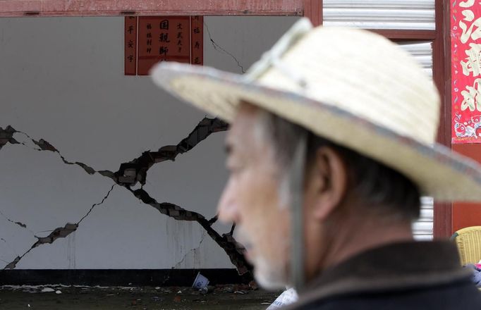 Cracks are seen on a wall as a villager stands in front of a damaged house on the second day after an earthquake hit Longmen township of Lushan county, Sichuan province April 21, 2013. Rescuers struggled to reach a remote corner of southwestern China on Sunday as the toll of the dead and missing from the country's worst earthquake in three years climbed to 203 with more than 11,000 injured. The 6.6 magnitude quake struck in Lushan county, near the city of Ya'an in the southwestern province of Sichuan, close to where a devastating 7.9 temblor hit in May 2008 killing some 70,000. REUTERS/Jason Lee (CHINA - Tags: DISASTER ENVIRONMENT) Published: Dub. 21, 2013, 10:37 dop.