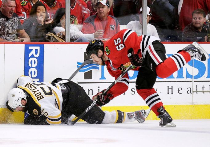 Boston Bruins Johnny Boychuk (55) is hit along the boards by Chicago Blackhawk Andrew Shaw (65) in the first period during Game 2 of their NHL Stanley Cup Finals hockey s