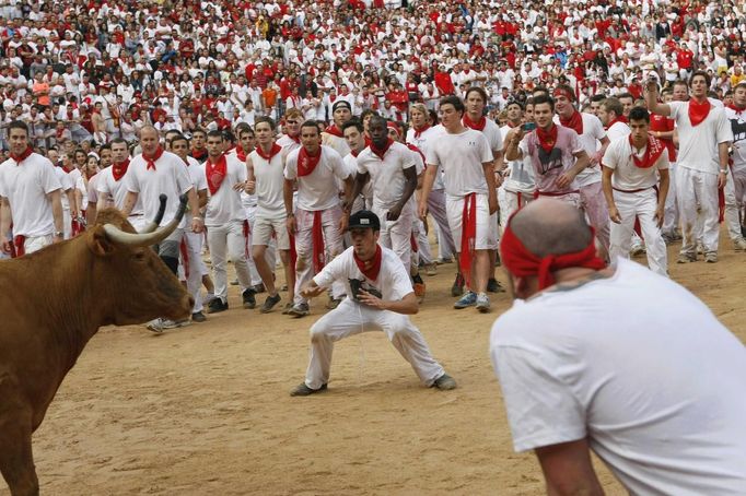 A reveller taunts a fighting cow in the Plaza de Toros, following the first running of the bulls of the San Fermin festival in Pamplona July 7, 2012. After the bull run, runners remain in the bullring and small fighting cows are released. REUTERS/Joseba Etxaburu (SPAIN - Tags: SOCIETY ANIMALS) Published: Čec. 7, 2012, 9:34 dop.