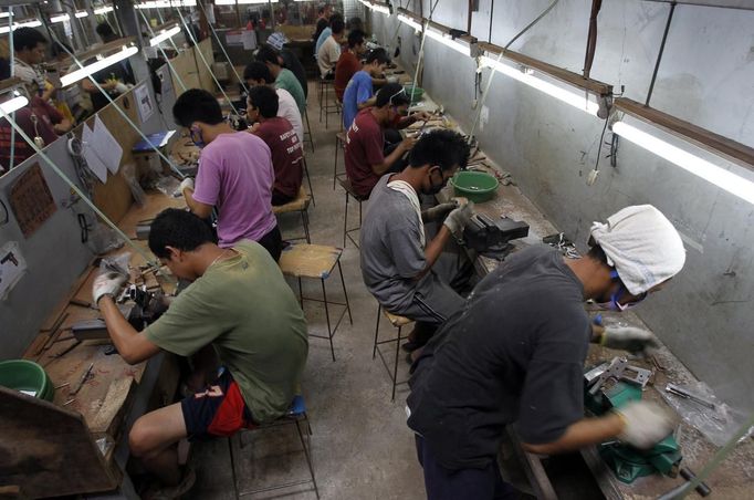 Former illegal gunsmiths work at the gun assembly line of Shooters Arms, a gun manufacturing company exporting different kinds of weapons to other countries, in Cebu city in central Philippines July 7, 2012. In the Philippines, they vote with their trigger fingers. Elections mean big business for illegal gunsmiths, who are looking forward to 2013 mid-term polls. With election-related violence commonplace, the Philippines imposes a ban on the carrying of guns for six months, from campaigning to the proclamation of winners. Picture taken July 7, 2012. To match Feature PHILIPPINES-GUNS/ REUTERS/Erik De Castro (PHILIPPINES - Tags: SOCIETY POLITICS BUSINESS CRIME LAW) Published: Čec. 29, 2012, 1:58 dop.