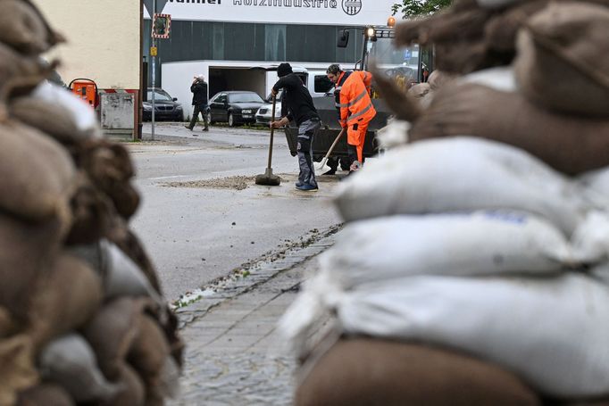 Lidé pracují na úklidu silnice po silných záplavách v Reichertshofenu.