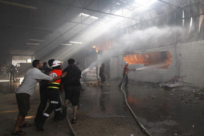 Firefighters try to extinguish a fire at a factory, which according to Palestinians was hit by an Israeli air strike in Gaza November 16, 2012. Egyptian Prime Minister Hisham Kandil, on a brief visit to the Gaza Strip on Friday, denounced Israel's attacks on the Palestinian territory and said Cairo would try to secure a ceasefire. Fighting continued along the Israel-Gaza border during Kandil's three-hour visit. REUTERS/Ahmed Zakot (GAZA - Tags: CIVIL UNREST MILITARY POLITICS) Published: Lis. 16, 2012, 9:31 dop.