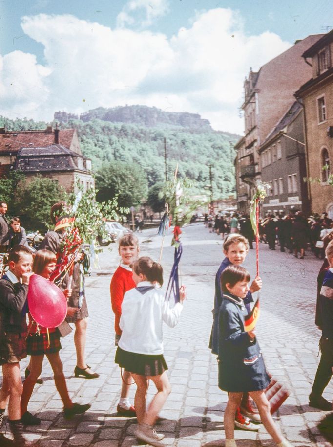 Děti s balónky a vlajkami na ulici v Königsteinu v Saském Švýcarsku, v pozadí hrad Königstein, NDR, 1969.